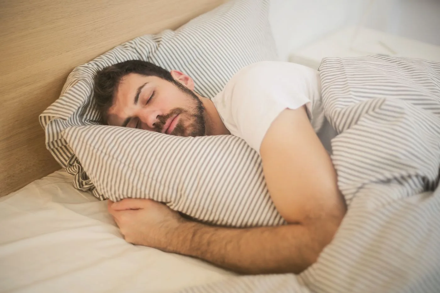 Seseorang mempraktikkan teknik pernapasan rileks sebelum tidur di kasurnya.